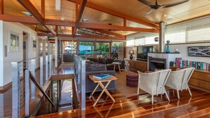 Amplia sala de estar con chimenea, televisor y estantería. Una escalera conduce a un nivel superior.