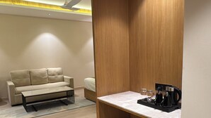 Un salon moderne comprenant un canapé, un coin café et un petit réfrigérateur.
