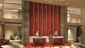 Un hall d’entrée moderne avec un comptoir d’accueil, un grand panneau rouge vertical et un lustre.
