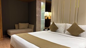 Une chambre d’hôtel avec un grand lit, un canapé, une table de chevet avec une lampe et un miroir.