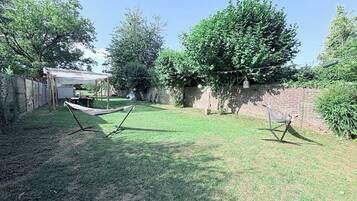 A backyard with a hammock, a pergola, and a brick wall.
