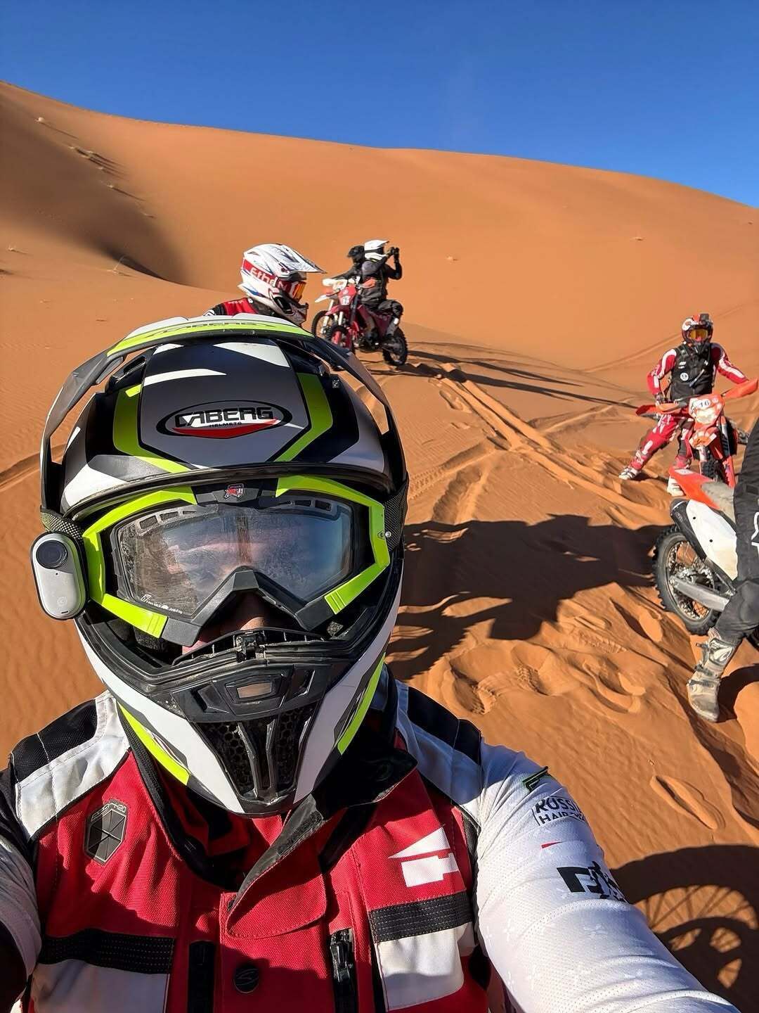 Paisaje desértico con dunas de arena y una persona en motocicleta.
