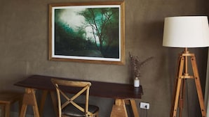 Une pièce comprenant un bureau en bois, une chaise, une lampe et un tableau encadré accroché au mur.