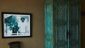 A vintage teal cabinet with intricate carvings, a framed black-and-white photograph on the wall, and a wooden chair with a curved backrest. - w Remarkable 1BR w Pool in M Ncora (Máncora)