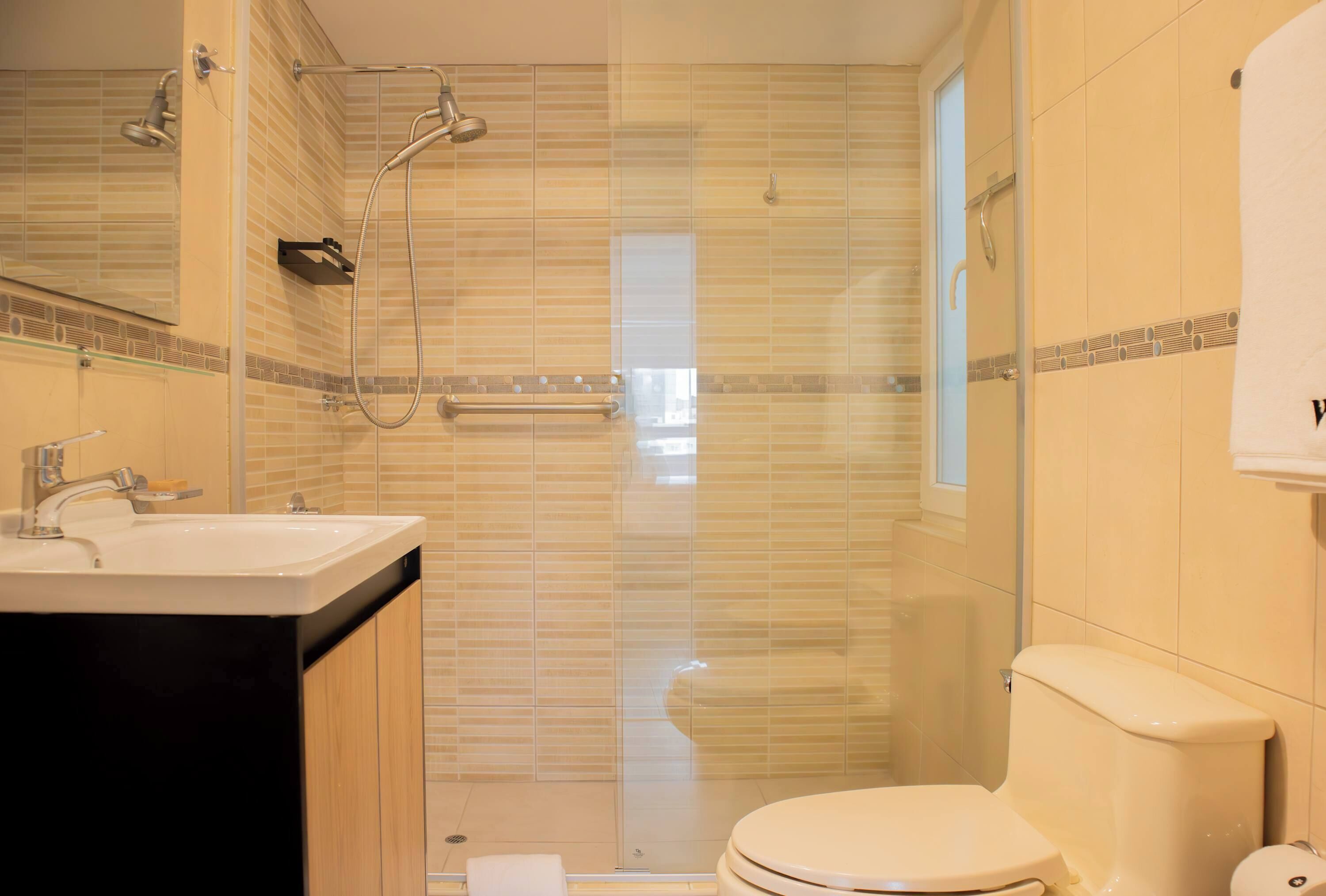 Une salle de bain équipée d’une douche, de toilettes, d’un lavabo et d’un miroir.