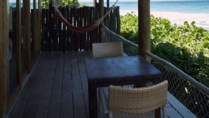 A wooden deck with a table and chairs, overlooking a beach with a hammock. - w Trendy 1BR w Pool in M Ncora (Máncora)