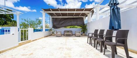Une terrasse sur le toit agrémentée d’une pergola, d’un espace salon et de plantes en pot.