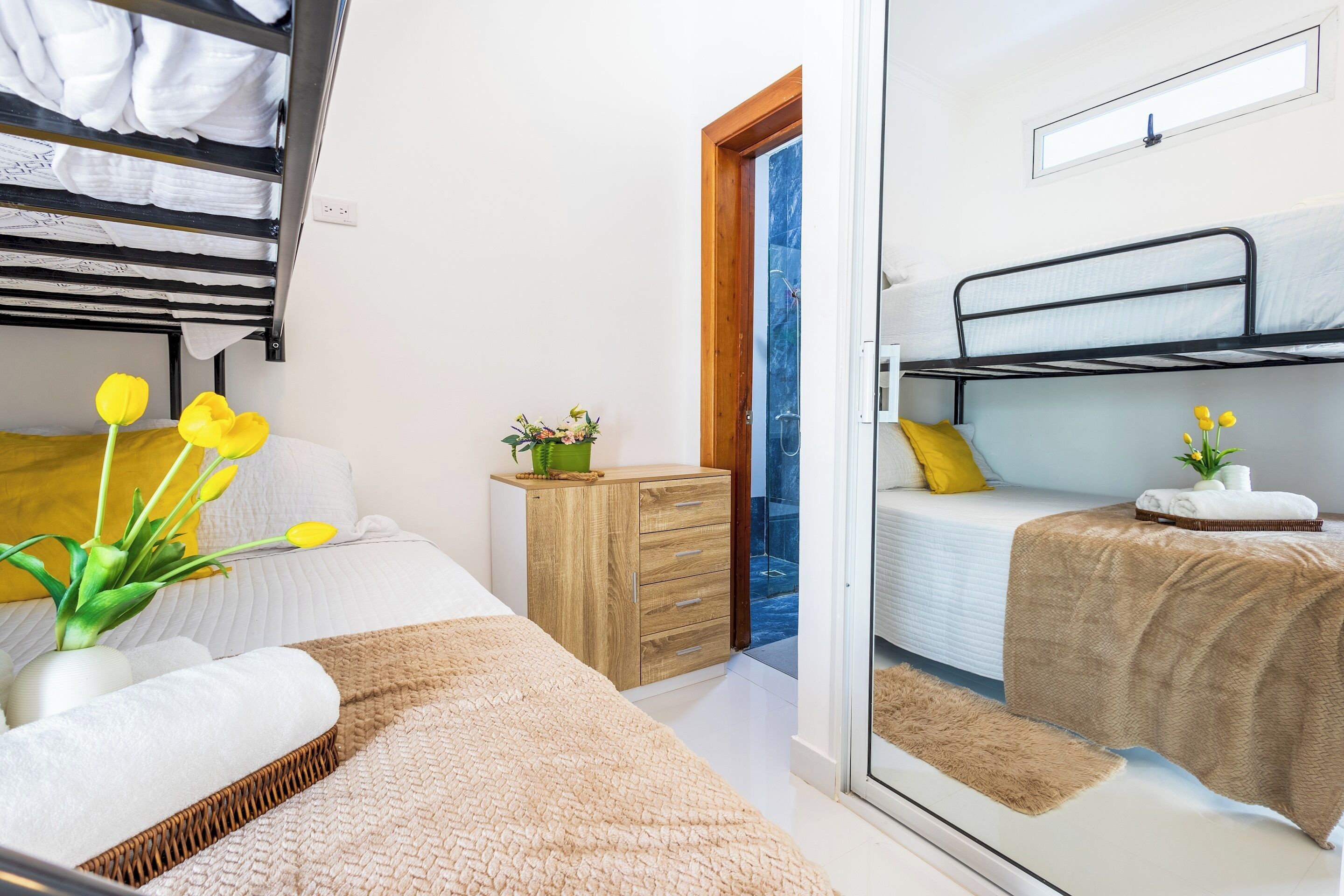 Une chambre avec un lit superposé, une table de chevet ornée d’une plante et une fenêtre donnant sur un beau paysage.