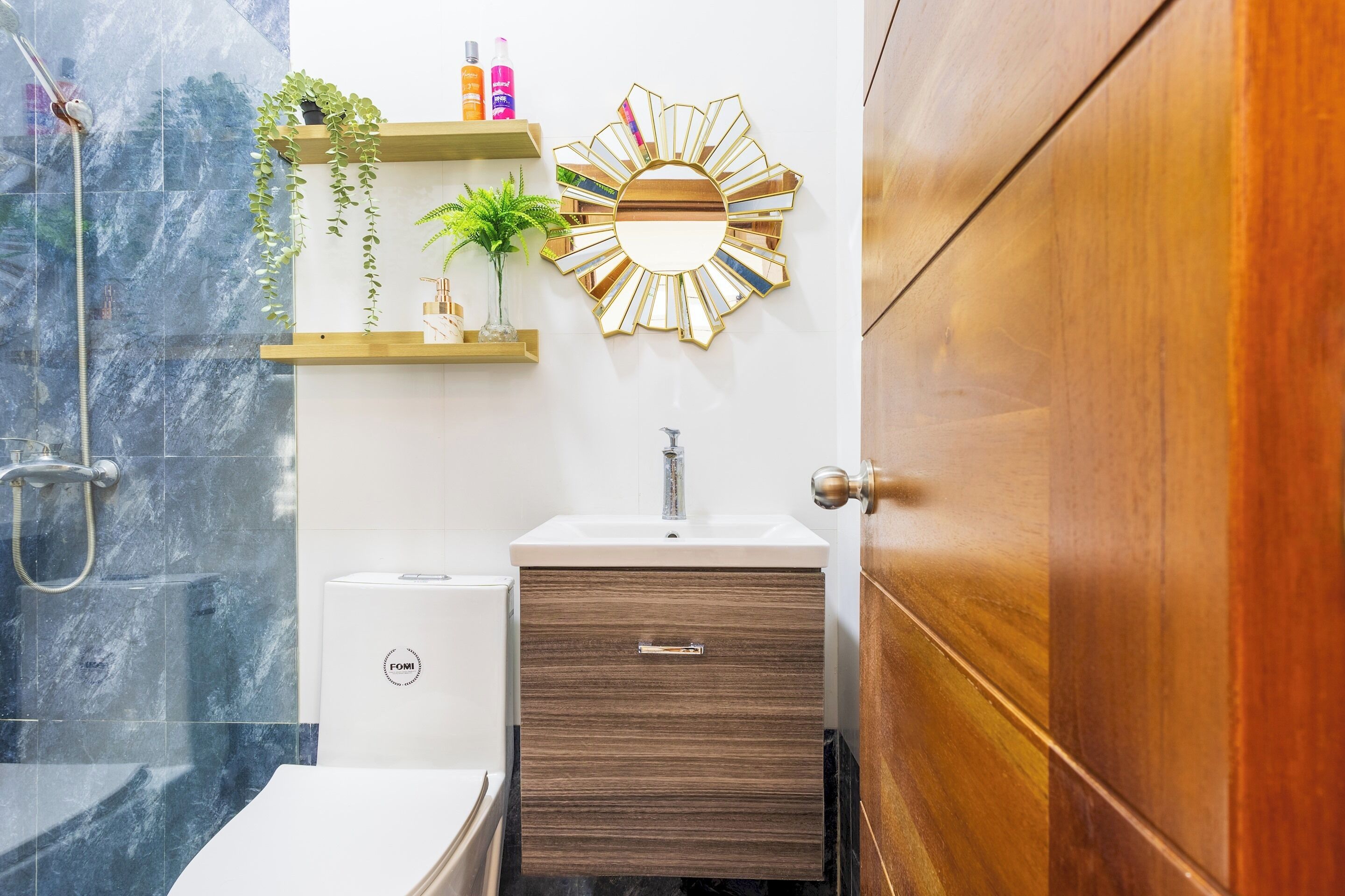 A bathroom with a shower, a sink, a mirror, and a wooden cabinet.