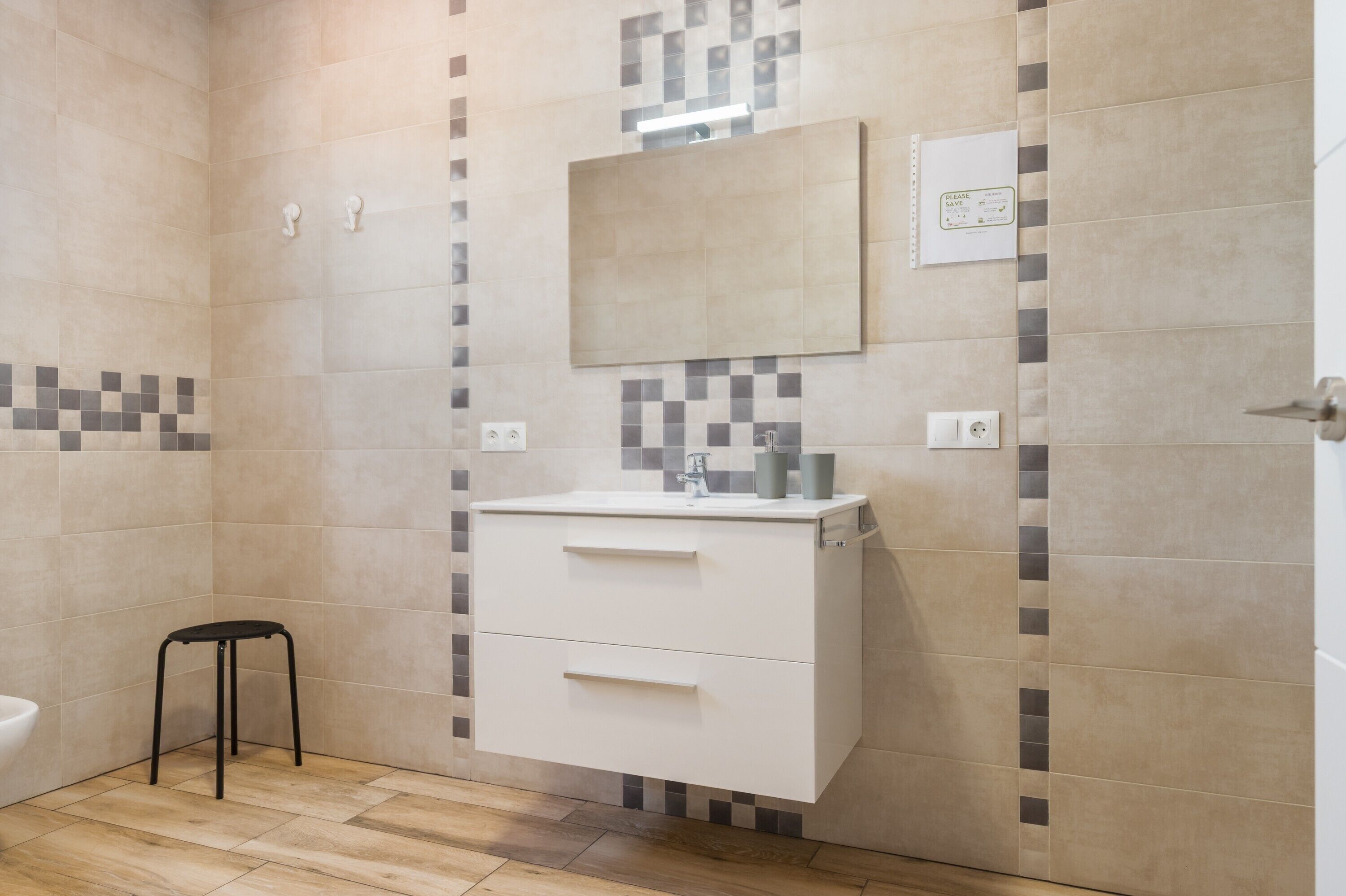 A bathroom with a white vanity, a mirror, and a tiled wall with a checkered pattern.