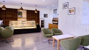 A modern interior with a wooden counter, green upholstered chairs, and a display case. - Garden Hills Hotel (Addis Ababa)