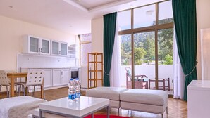 A modern hotel room with a kitchenette, a dining area, and a large window with curtains. - Garden Hills Hotel (Addis Ababa)