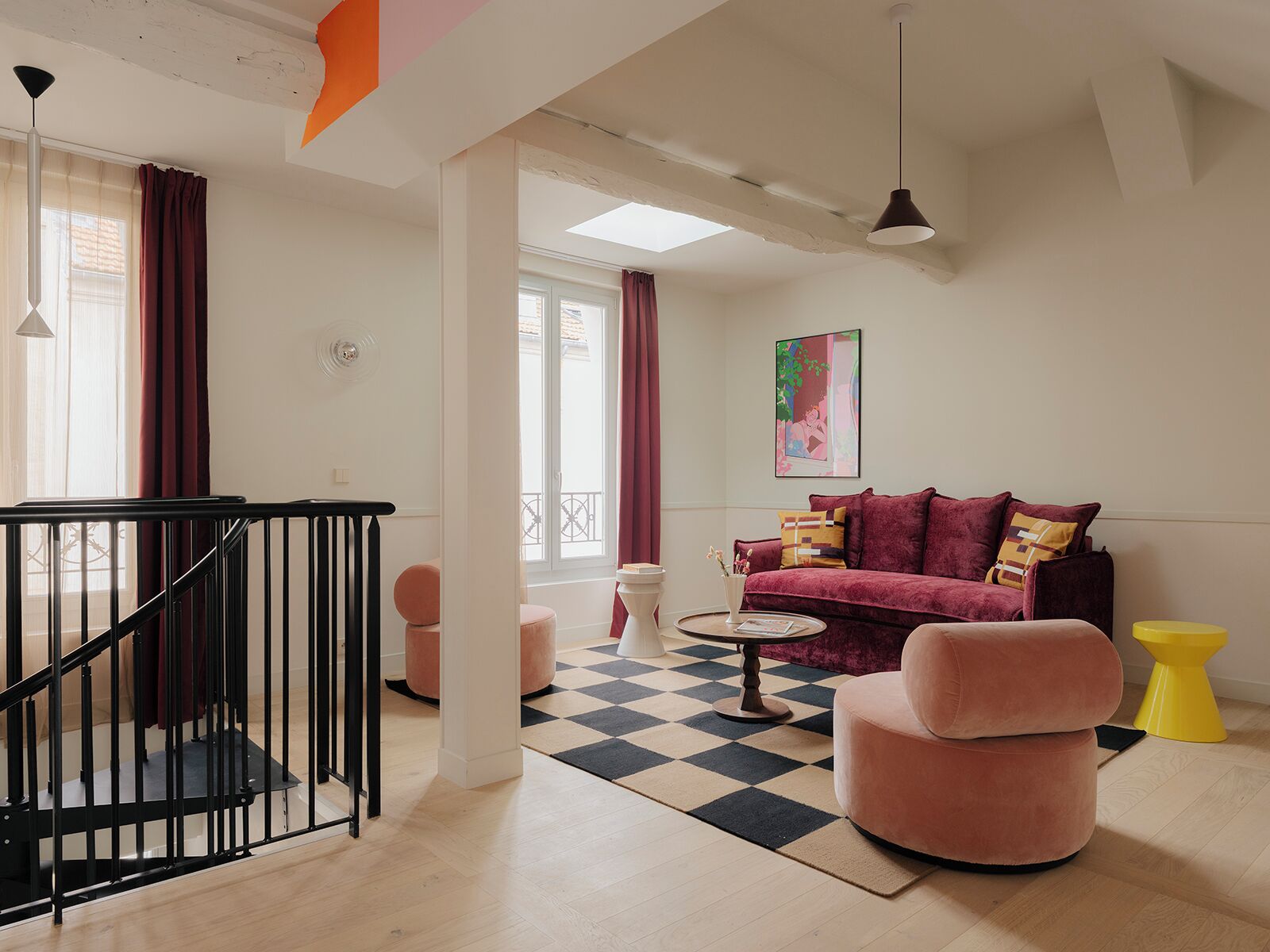 Una sala moderna con una escalera, un conjunto de sofás y un suelo a cuadros.