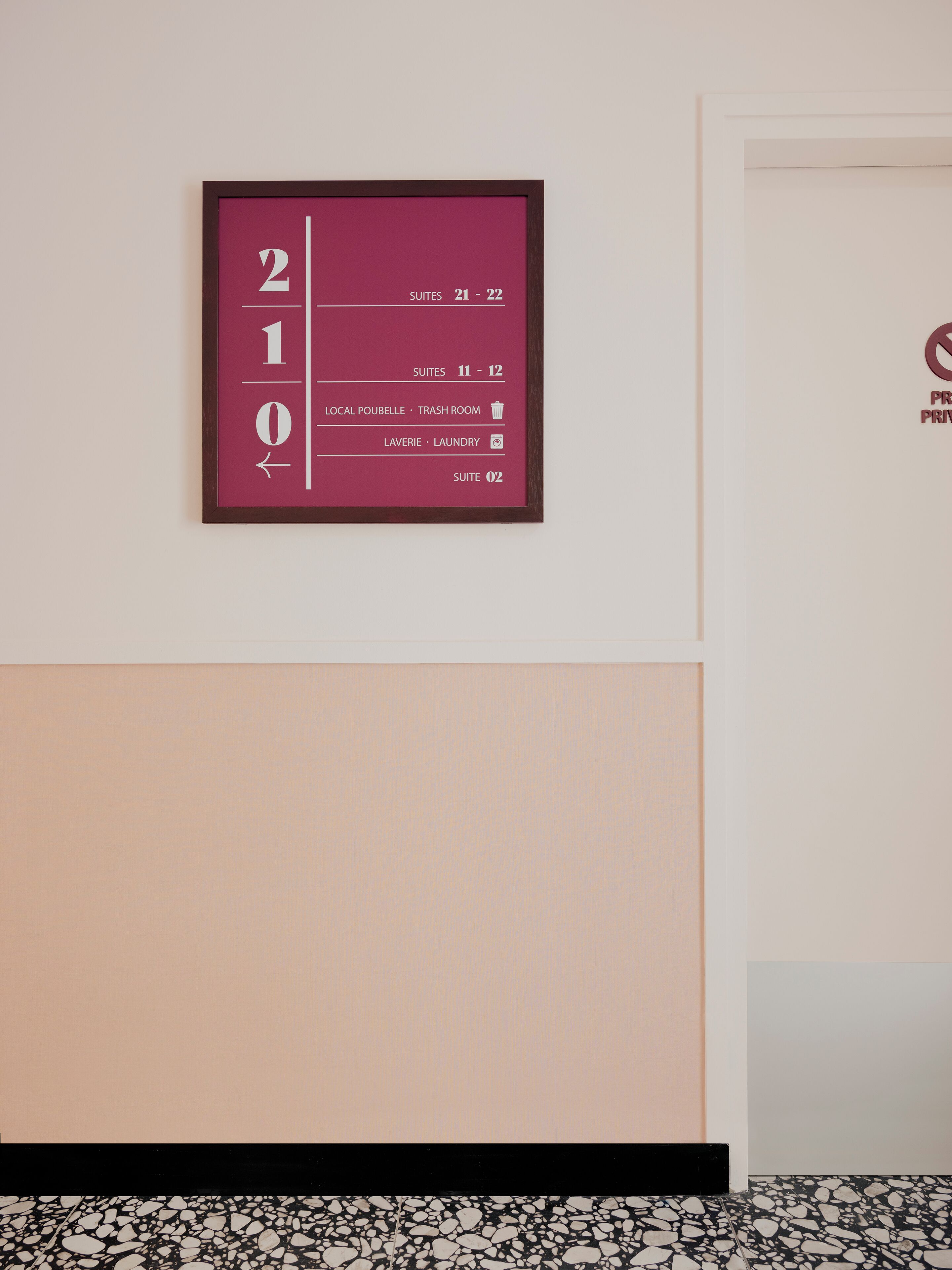 A wall with a numbered sign indicating room numbers and amenities.