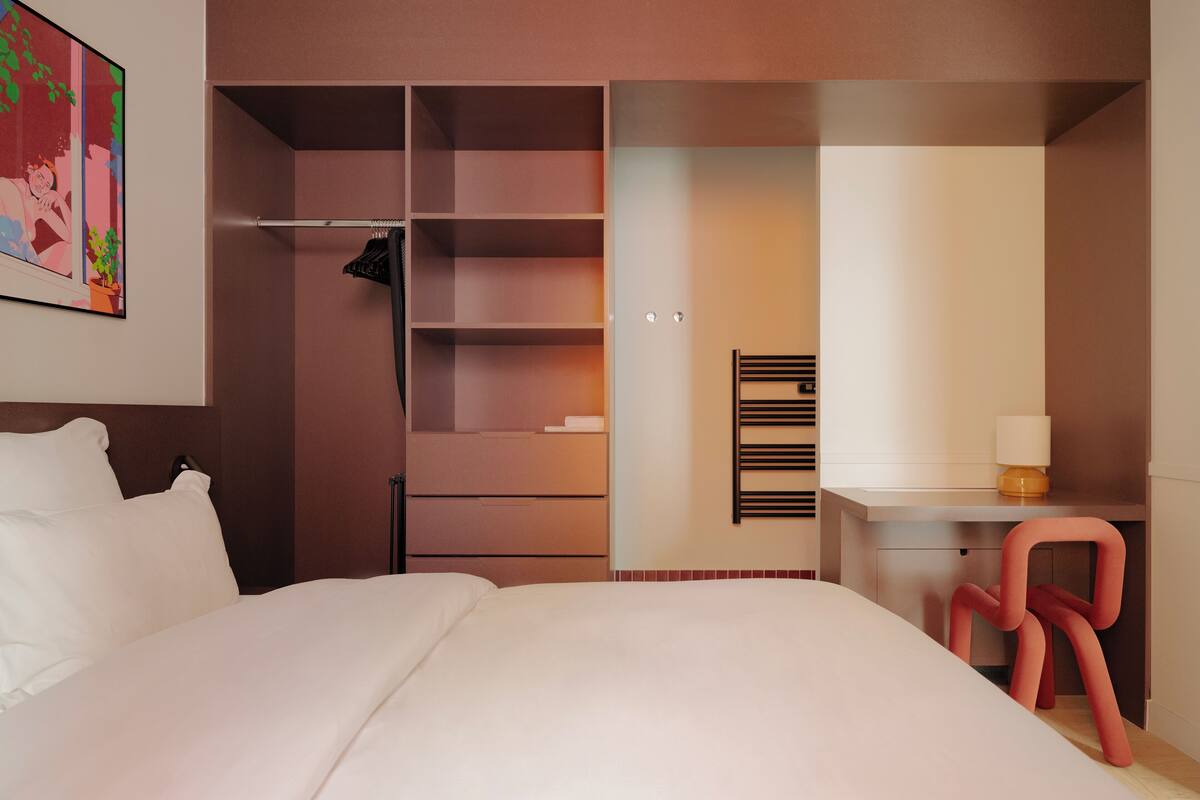 A bedroom with a bed, a desk, a chair, and a wardrobe.