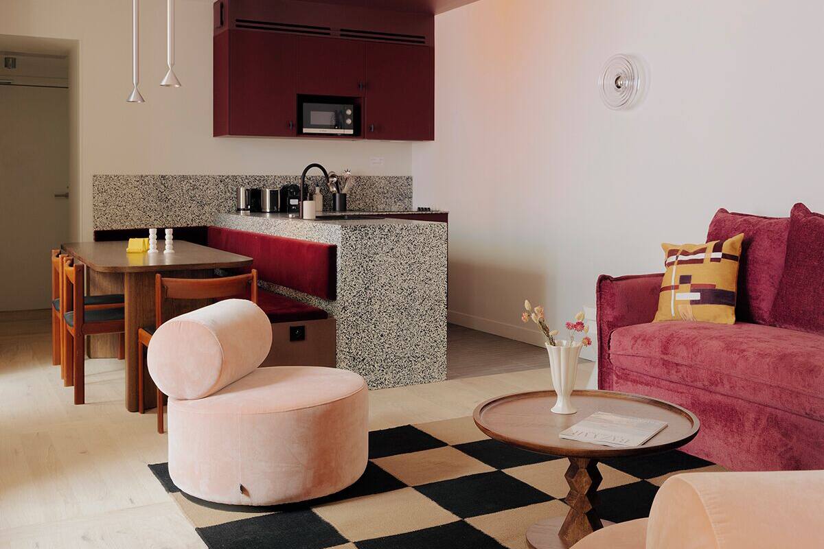 A compact living space with a kitchenette, a dining area, and a seating area with a checkered rug.