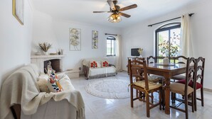 Un salon spacieux avec une cheminée, un coin repas doté de meubles en bois et un ventilateur de plafond.