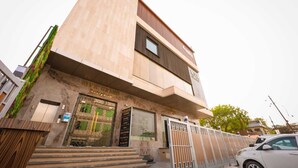A modern building with a large entrance, steps leading up to it, and a gated driveway. - MVR Grand Hotel (Kanpur)