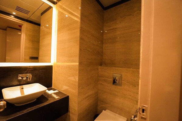A bathroom with a sink, mirror, and shower. - MVR Grand Hotel (Kanpur)