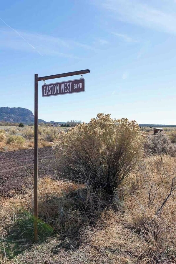 Wegwijzer voor Easton West Blvd in een droog, open landschap met weinig begroeiing en bergketens in de verte.