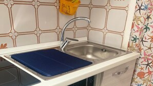 A kitchen with a stainless steel sink, a blue cutting board, and an open dishwasher. - CASA DONNA CONCETTA (Positano)