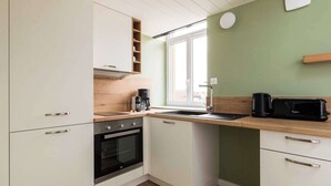 A compact kitchen with white cabinets, a built-in oven, a coffee maker, and a microwave on the countertop. - Dify Sunny - 10 Min Centre de Lyon (Villeurbanne)