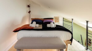 A bedroom with a bed, pillows, a bench, a wall-mounted lamp, and a painting. - Dify Sunny - 10 Min Centre de Lyon (Villeurbanne)