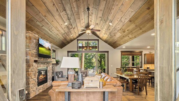Un espacio habitable amplio con chimenea de piedra, techo de madera y un sofá moderno.