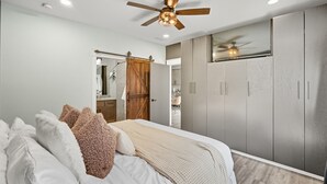 Une chambre à coucher avec un lit, des oreillers, un ventilateur de plafond et une armoire.