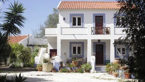 A two-story building with a tiled roof, a balcony on the upper floor, and a front entrance with a door. There are potted plants and a small staircase leading to the entrance. - Sintra Farm Villa Guest House (Sintra)