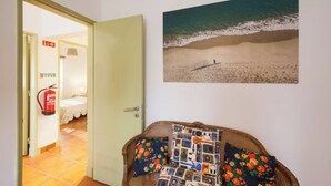 A room with a wicker sofa, a wall-mounted picture of a beach, and a visible exit sign. - Sintra Farm Villa Guest House (Sintra)