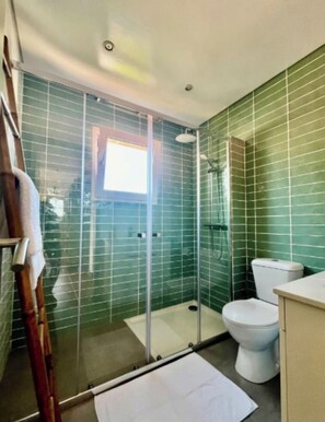 A bathroom with green tiled walls, a glass shower enclosure, a white toilet, and a wooden ladder leaning against the wall. - Sintra Farm Villa Guest House (Sintra)