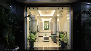 A hotel reception area with a glass door, potted plants, a red carpet, and a modern interior design. - The Basil Hotel (Udaipur)