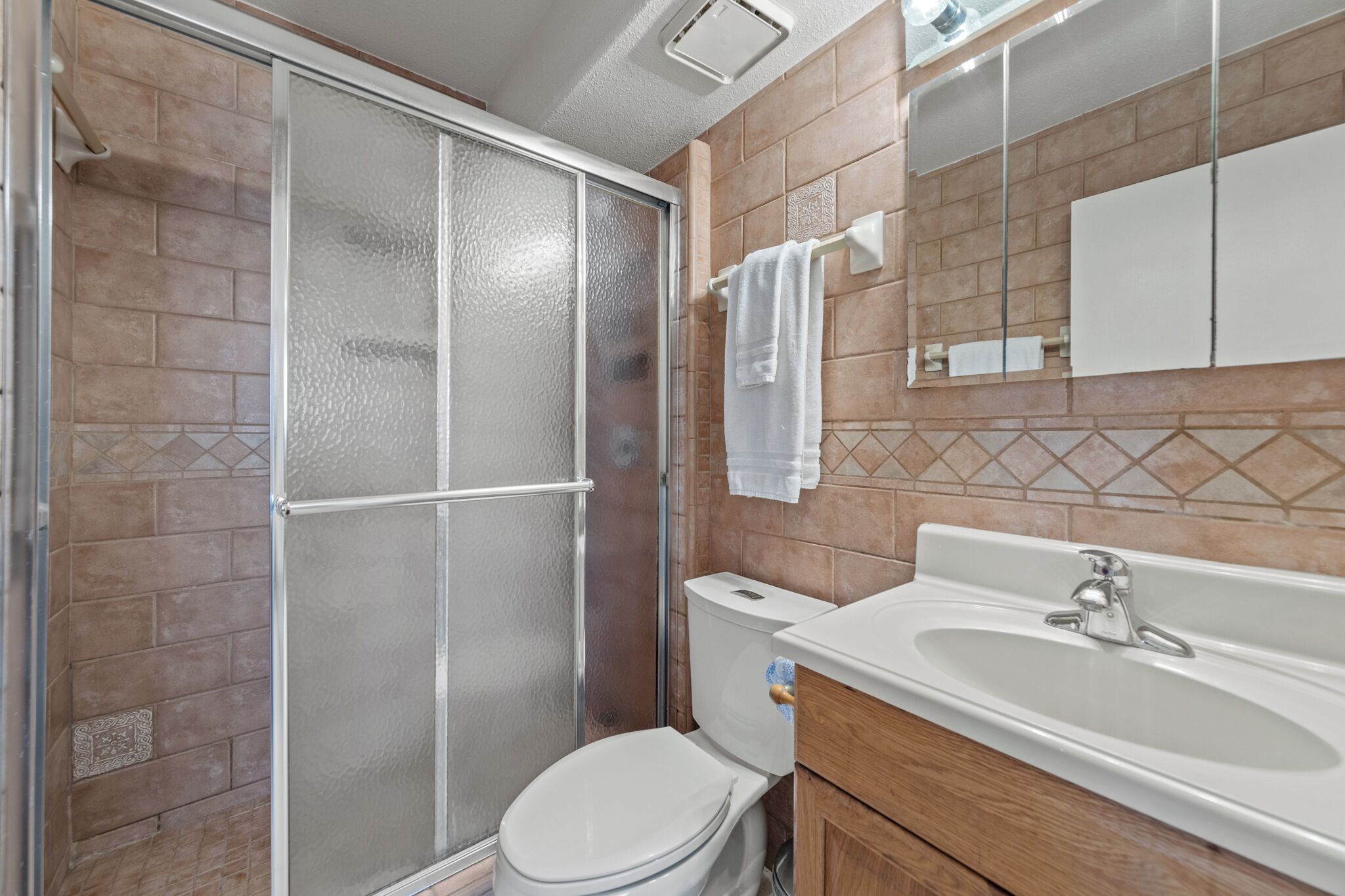 Une salle de bain avec une douche à parois de verre, des toilettes et un lavabo avec un miroir au-dessus.