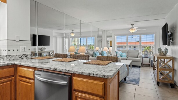 A modern kitchen with a large island, wooden cabinets, and a built-in dishwasher.