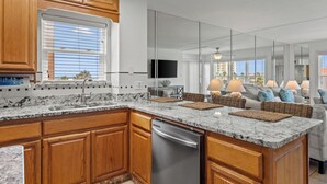 A modern kitchen with wooden cabinets, a marble countertop, and a built-in dishwasher.