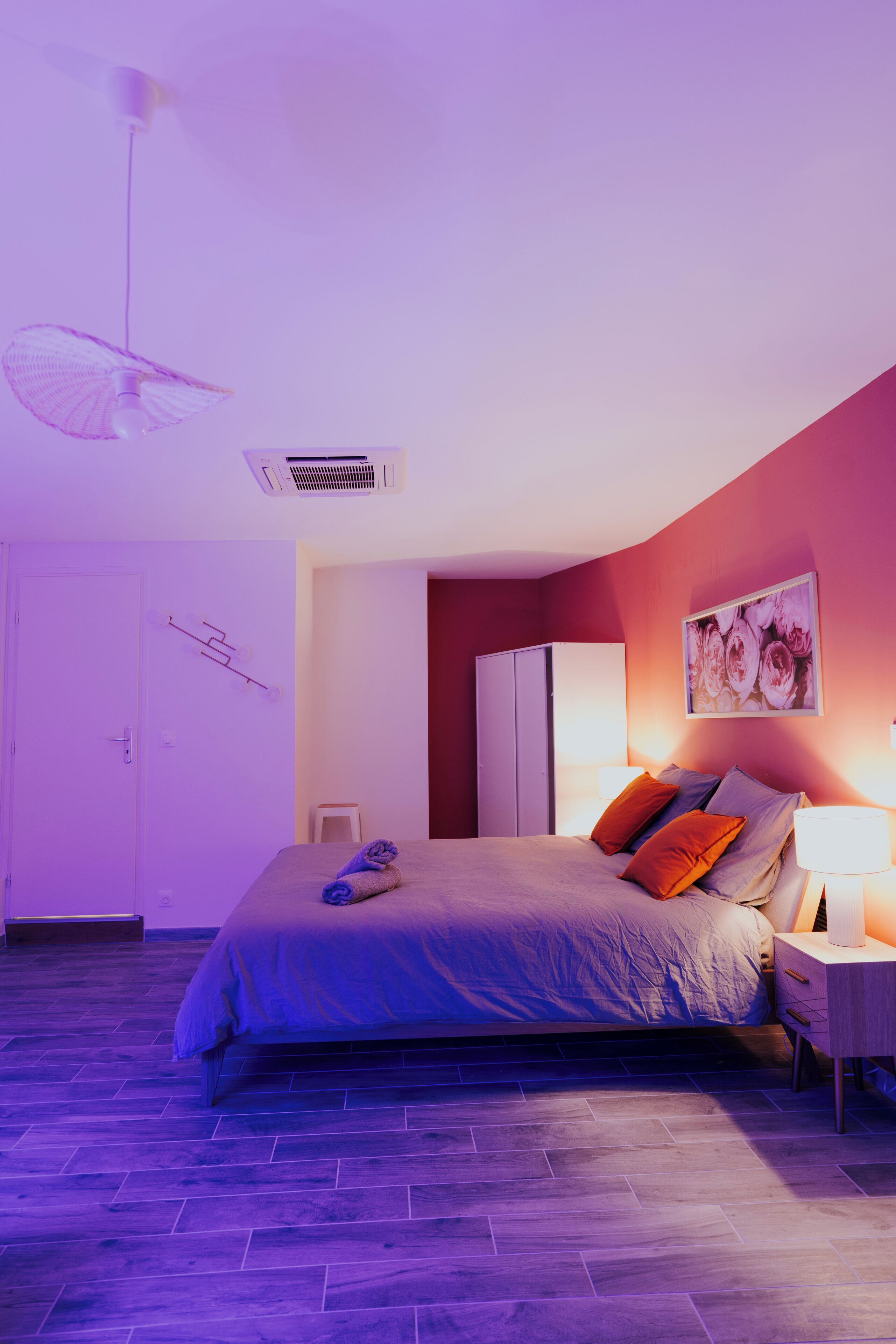 Ein Schlafzimmer mit Bett, Nachttisch, Wand-Klimaanlage, Deckenventilator und einer Tür.
