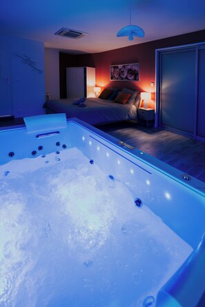 Une chambre d’hôtel moderne dotée d’une grande baignoire, d’un lit avec une table de chevet et d’une armoire.