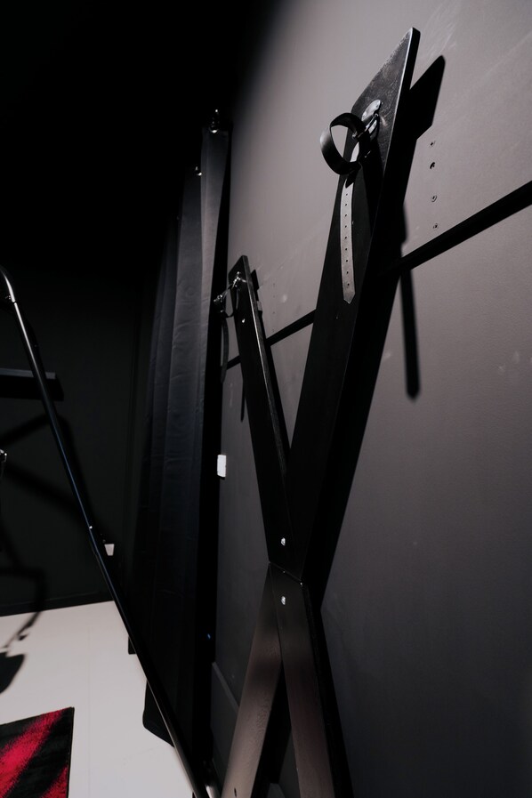 Une pièce dotée d’un grand miroir, d’un cadre en métal noir et d’un luminaire fixé au mur.