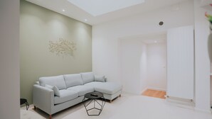 Una sala de estar moderna con un sofá seccional gris claro, una mesa de centro redonda y una obra de arte abstracta colgada en la pared.