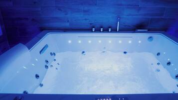 Une salle de bain moderne avec une baignoire sur pieds, un panneau de commande et un mur en bois.