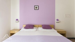 A bedroom with a bed, two nightstands, and a wall-mounted picture. - albergo Atene (Riccione)