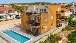 A modern multi-story building with a swimming pool, balconies, and a view of the surrounding neighborhood. - Cozy apartment in Vir with outdoor swimming pool (Vir)