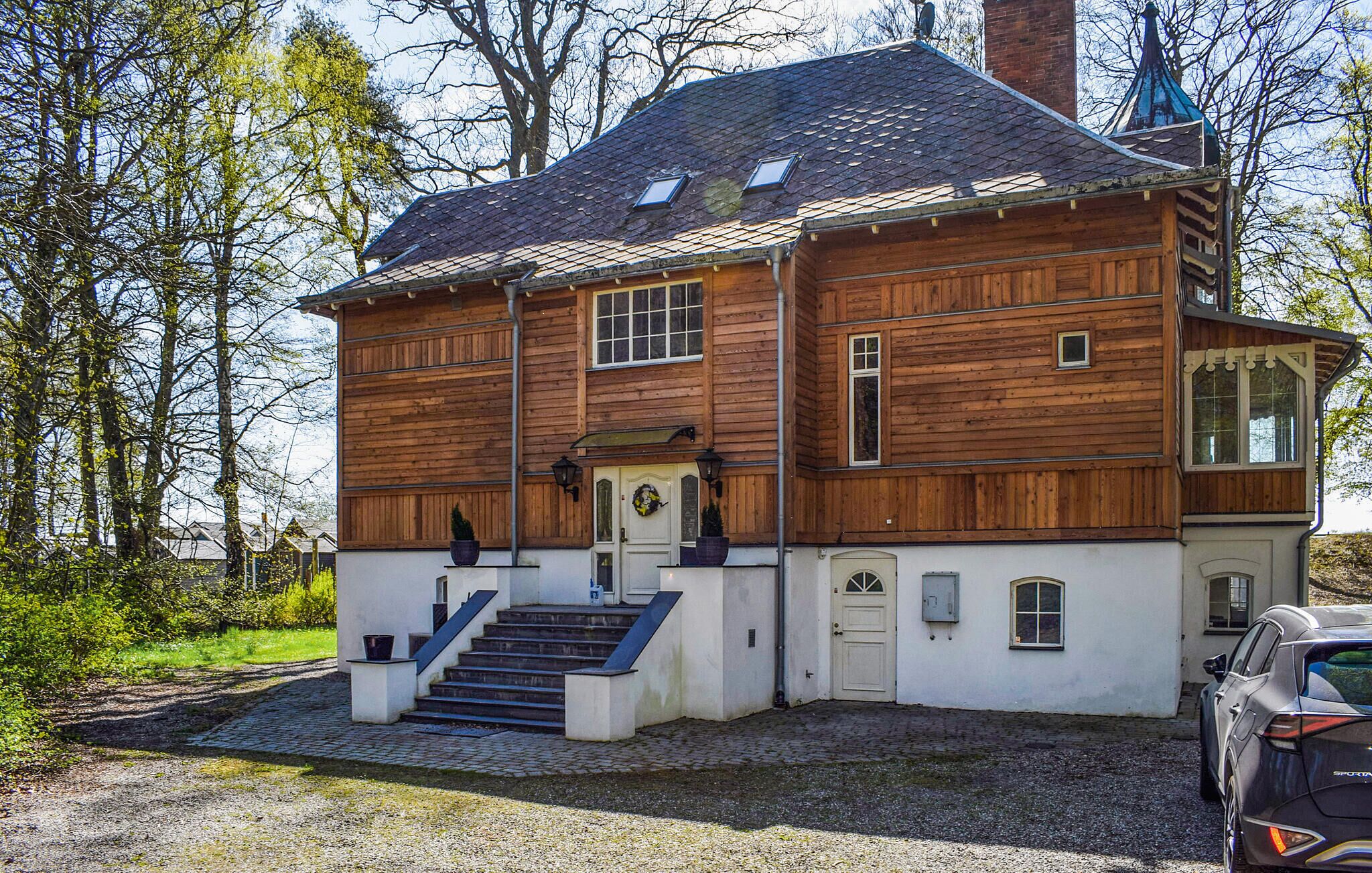 A two-story wooden house with a white exterior, a chimney, and a car parked in front.