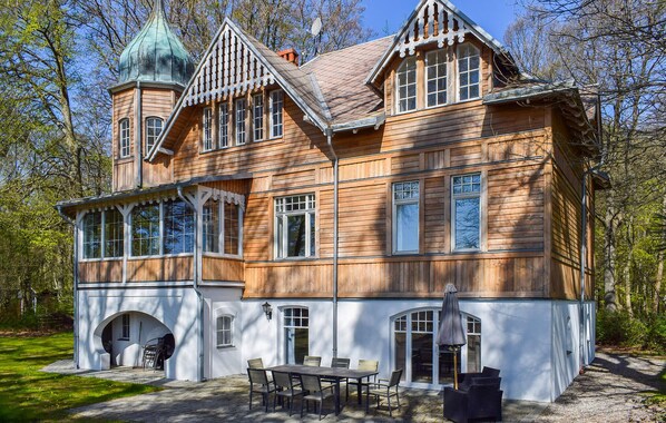 A large wooden house with a tower, multiple windows, and a covered outdoor seating area. - Lovely apartment in Ystad with WiFi (Ystad)