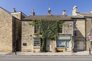A stone building with ivy covering the windows, a closed shutter, and a visible door. - Stylish and sophisticated holiday apartment - Flat 2 Martins House (Stow-on-the-Wold)