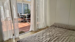 A bedroom with a bed, a sliding glass door leading to an outdoor patio with a table and chairs, and a potted plant. - CASA EVA - MAS PINELL (Torroella de Montgri)