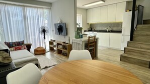 A modern living room with a round wooden table, white sofas, and a dining area. - CASA EVA - MAS PINELL (Torroella de Montgri)