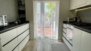 A modern kitchen with white cabinets, a black countertop, and a large window with a view of the outdoors. - CASA EVA - MAS PINELL (Torroella de Montgri)