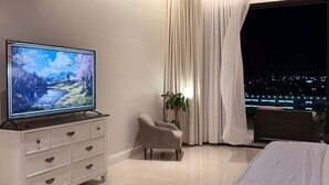 A modern bedroom with a flat-screen TV, a bed, a sofa, and a large window with curtains. - Amazing studio with charming view in charming Taif (Taif)
